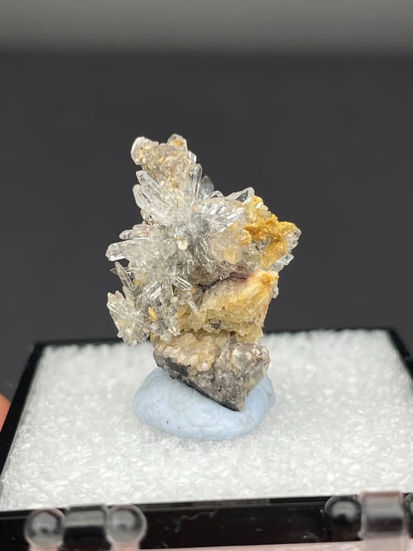 Colourless radiating creedite needle spray from Guizhou, China, in a display box