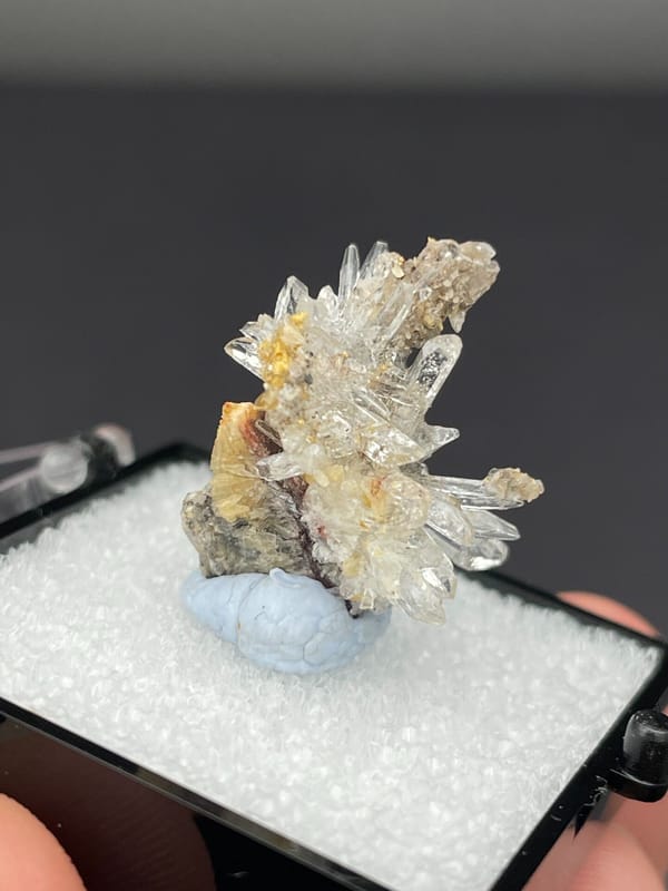 Colourless radiating creedite needle spray from Guizhou, China, in a display box, reverse side