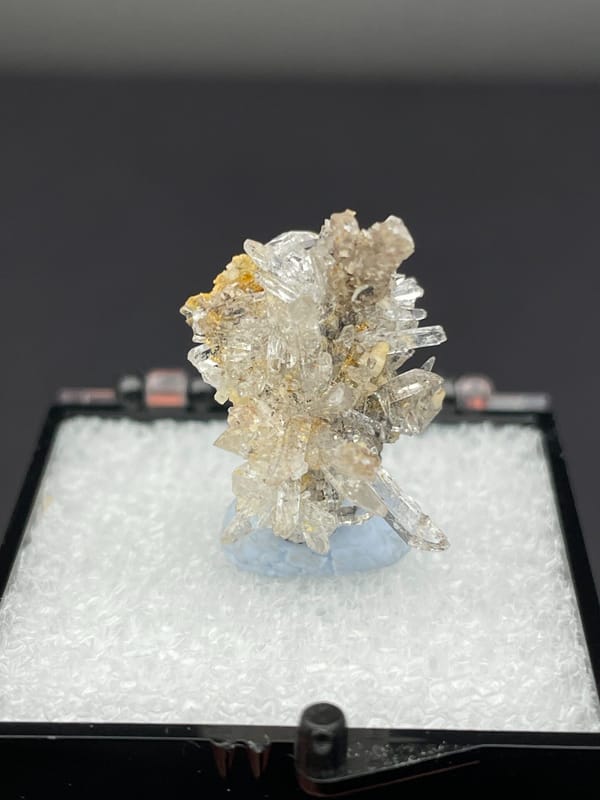 Colourless radiating creedite needle spray from Guizhou, China, in a display box, top view