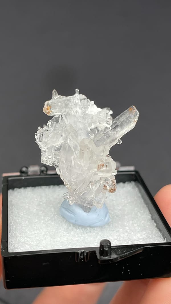 Colourless glassy creedite crystal spray from Guizhou, China, in a display box, top view