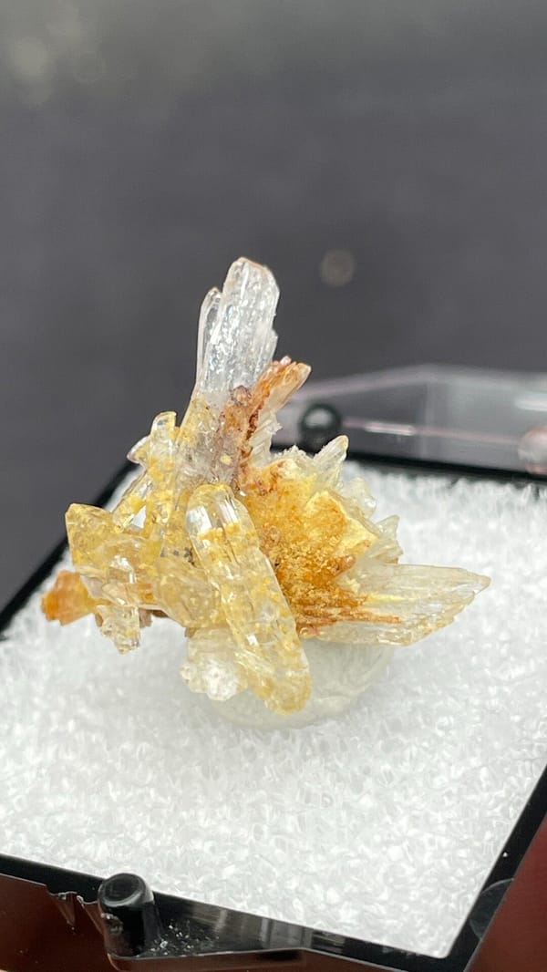Colourless and amber creedite and gypsum spray from Guizhou, China, in a box, close-up of the crystal faces