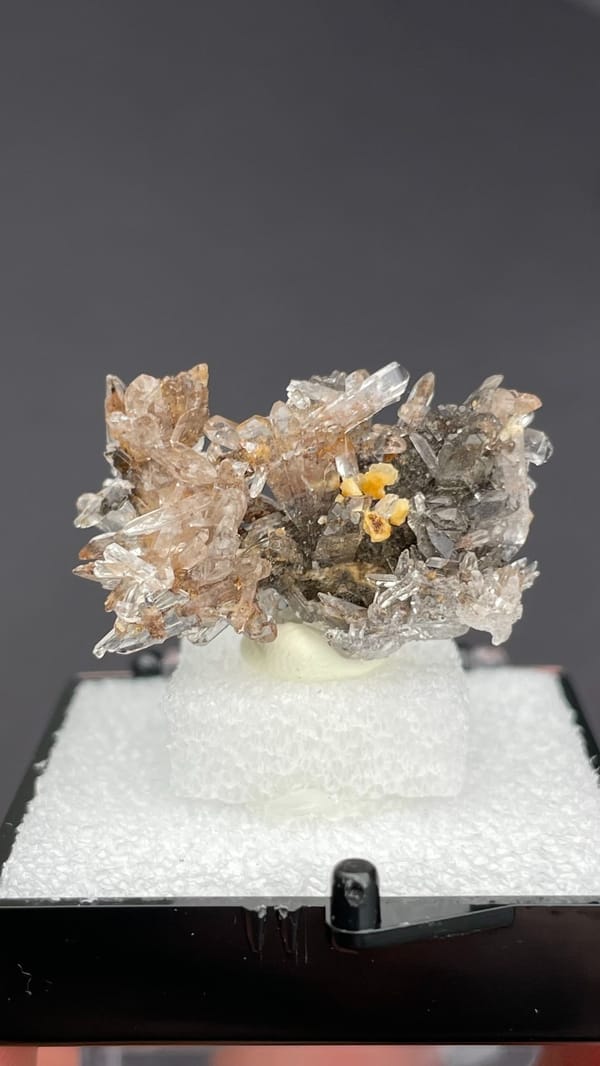 Colourless creedite spray around a small yellow stone from Guizhou, China