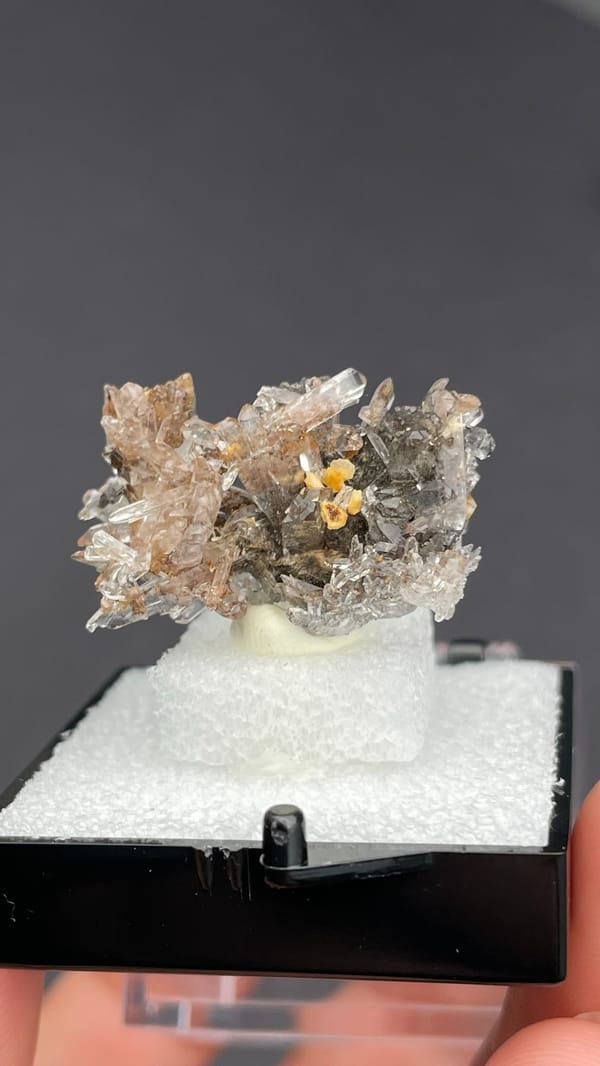 Colourless creedite spray around a small yellow stone from Guizhou, China, close-up of the crystal faces