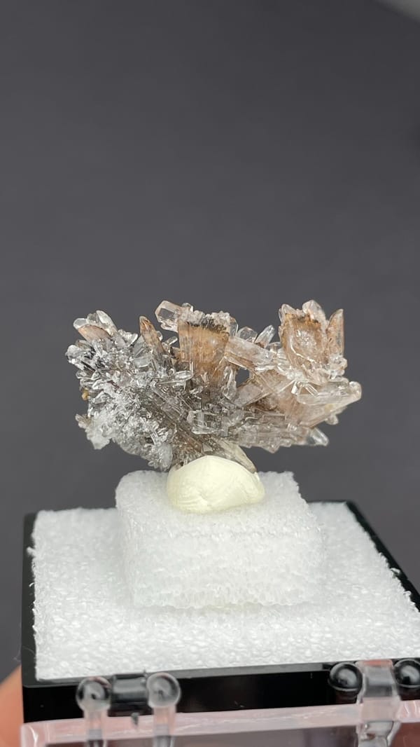 Colourless creedite spray around a small yellow stone from Guizhou, China, detail of the matrix contact