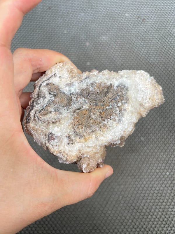 Large white creedite crystal crust on pale base from Guizhou, China, detail of the matrix contact