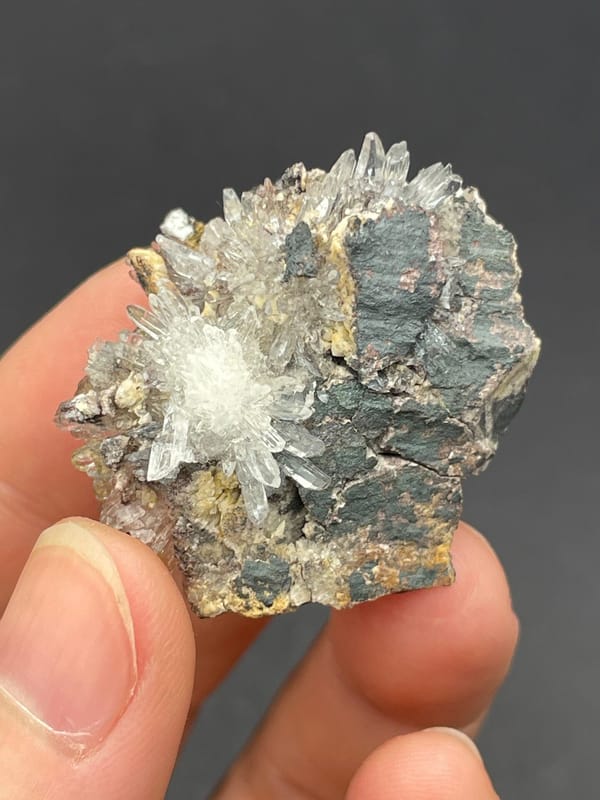 White creedite needle sprays on a grey-brown rock from Guizhou, China, second angle