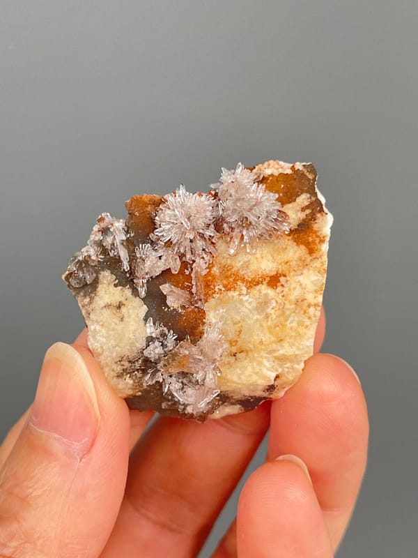Pale creedite needle sprays on ochre-orange rock from Guizhou, China, second angle