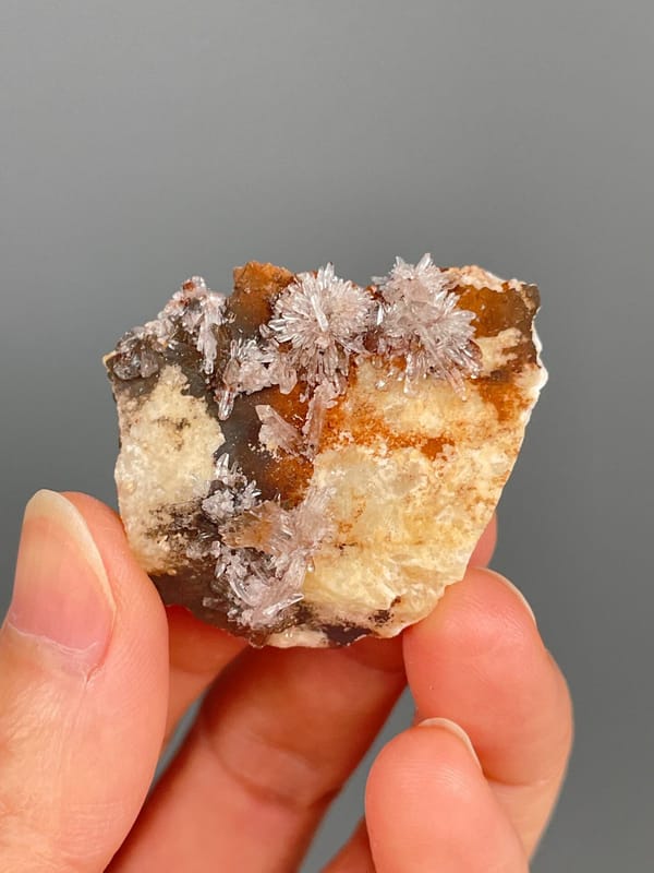 Pale creedite needle sprays on ochre-orange rock from Guizhou, China, top view