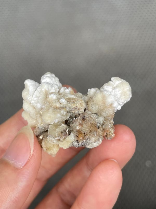 Cream popcorn-textured creedite crust from Guizhou, China, held in hand