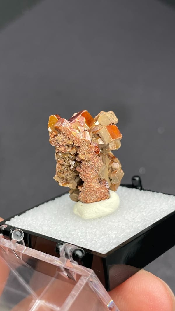Blocky orange-brown vanadinite crystal group from Morocco, in a display box, close-up of the crystal faces