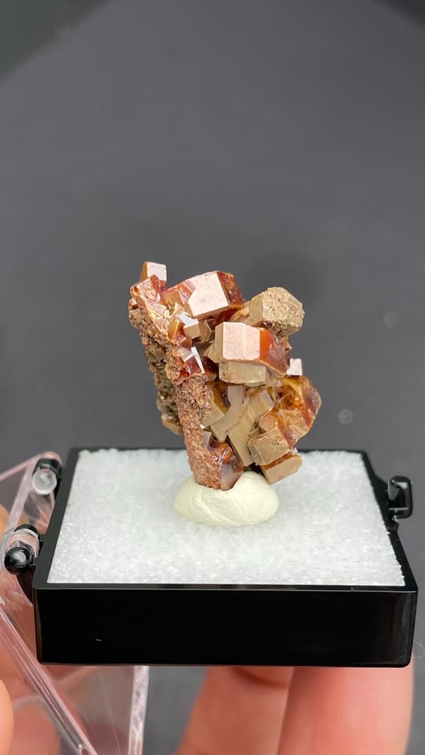 Blocky orange-brown vanadinite crystal group from Morocco, in a display box, reverse side