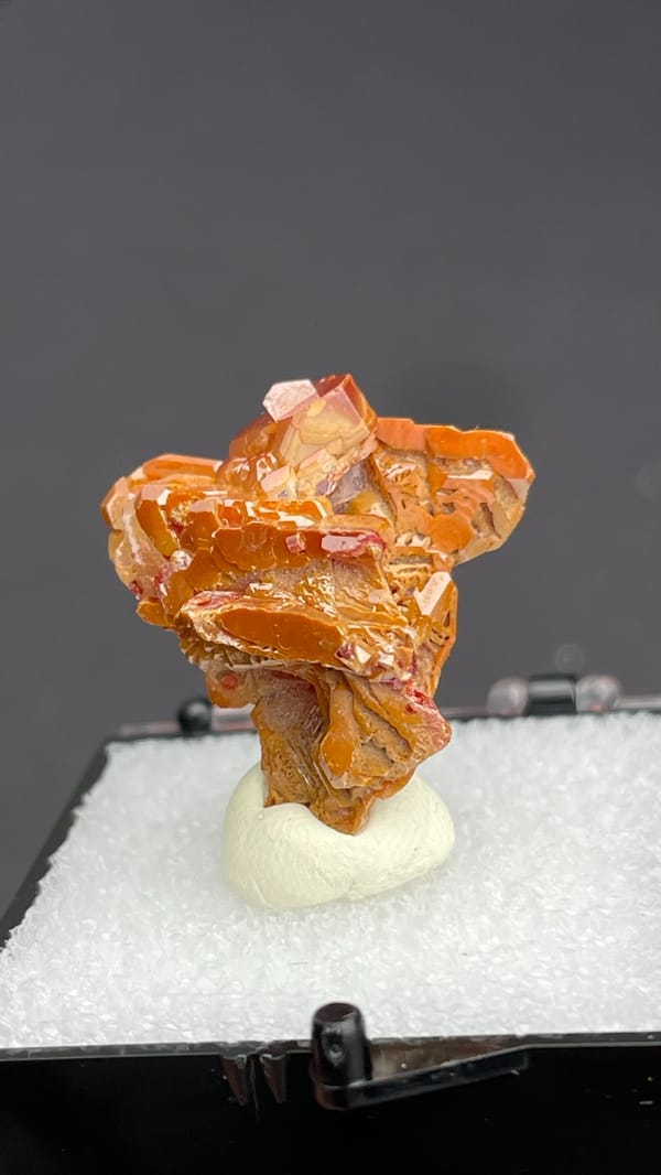 Layered orange-red vanadinite crystals from Morocco, in a display box