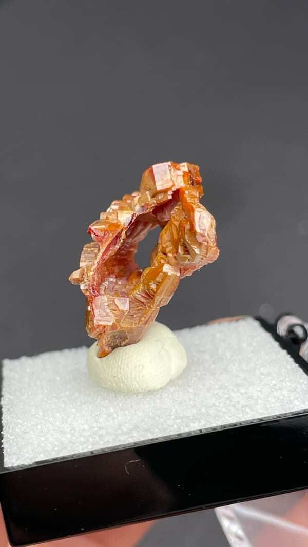Layered orange-red vanadinite crystals from Morocco, in a display box, reverse side
