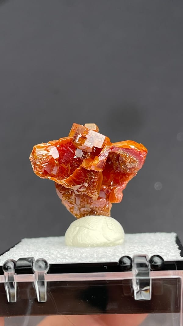 Layered orange-red vanadinite crystals from Morocco, in a display box, top view