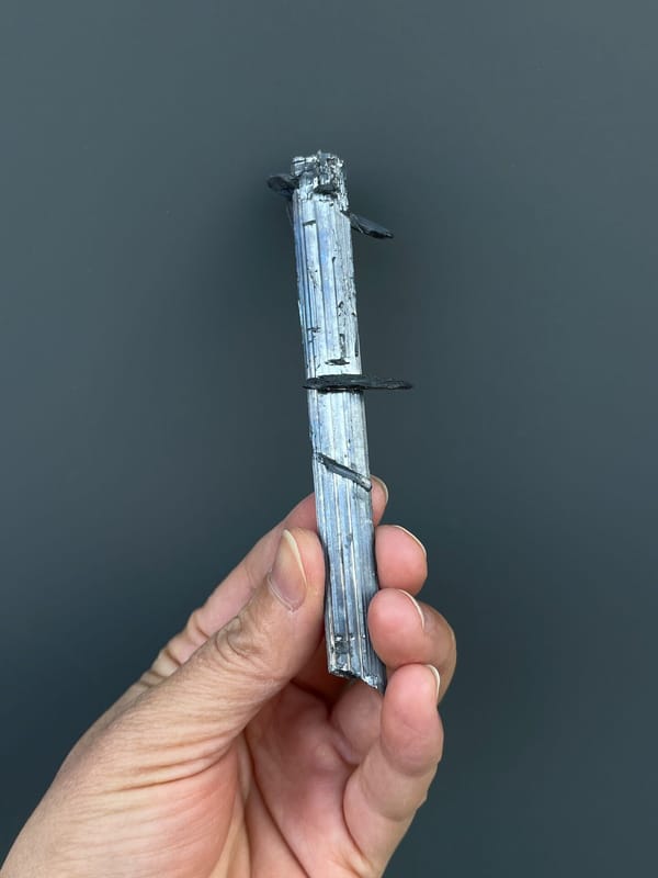 Long silver-grey striated stibnite blade from Yunnan, China, close-up of the crystal faces