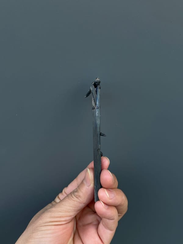 Long silver-grey striated stibnite blade from Yunnan, China, detail of the matrix contact