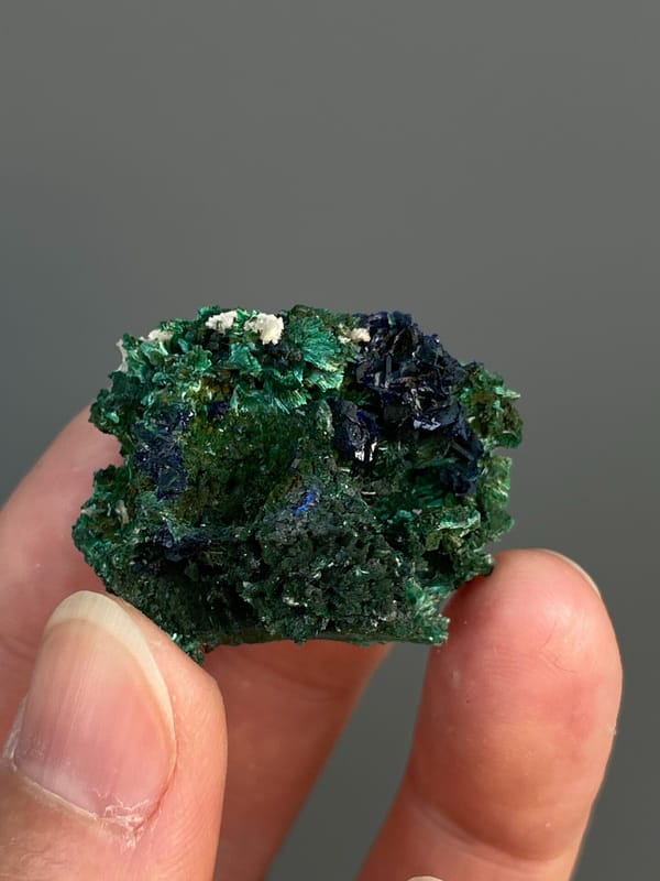Deep blue azurite crystals in green malachite from Anhui, China, held in hand