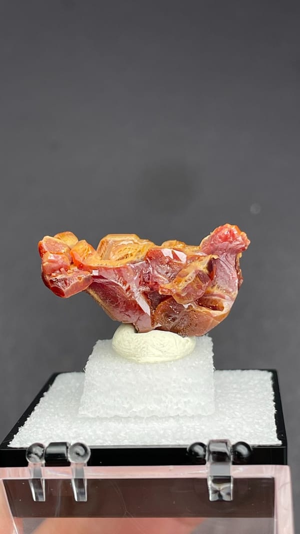 Orange vanadinite plates standing on a tan matrix from Morocco, in a box, top view