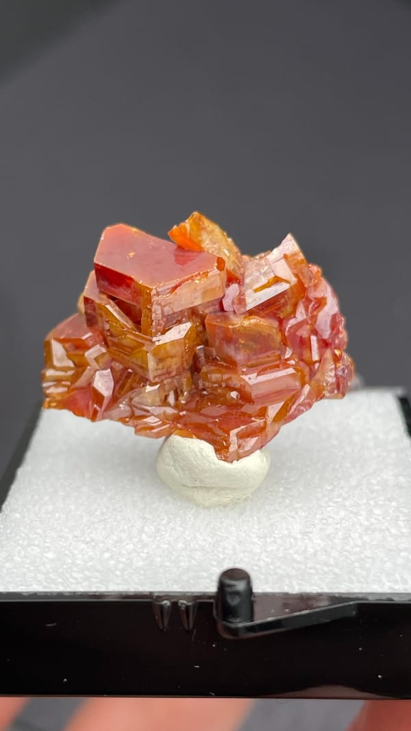 Stacked orange-red vanadinite plates from Morocco, in a display box, second angle