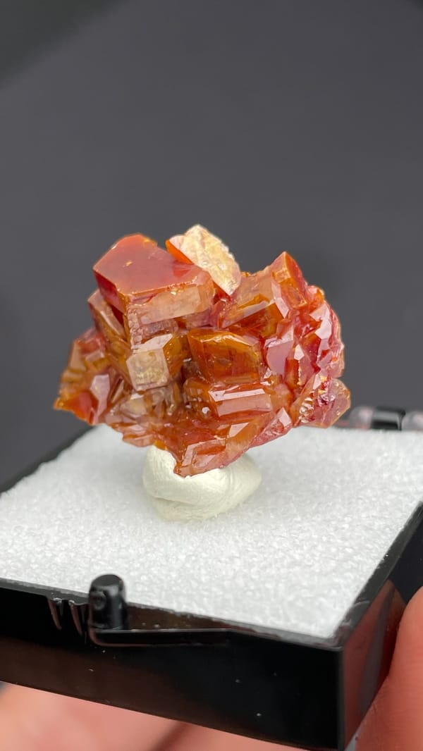 Stacked orange-red vanadinite plates from Morocco, in a display box, close-up of the crystal faces