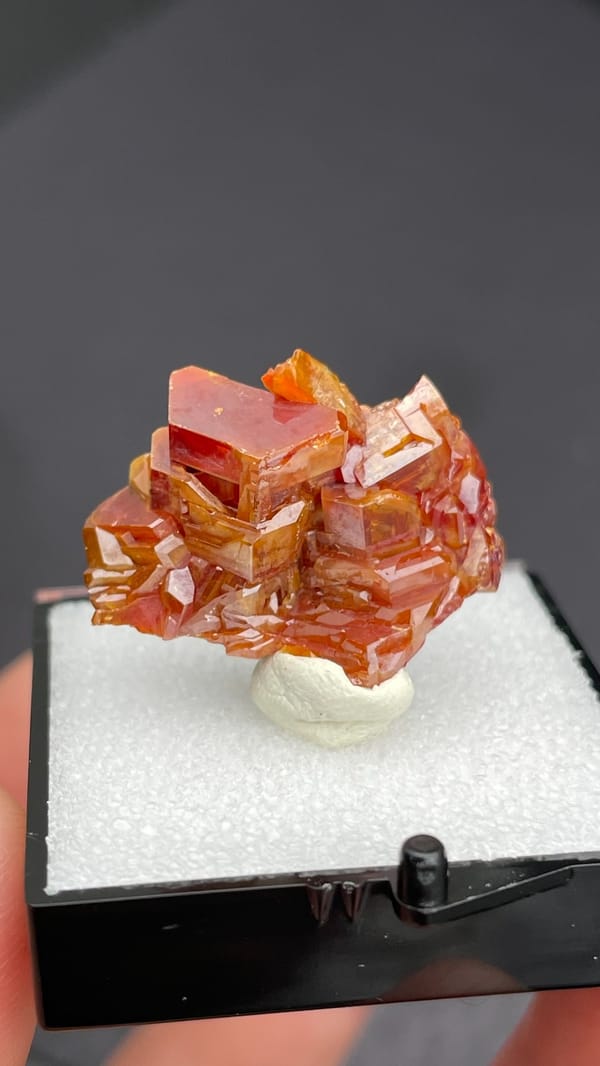 Stacked orange-red vanadinite plates from Morocco, in a display box, reverse side