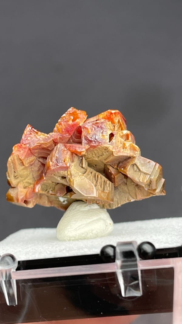Stacked orange-red vanadinite plates from Morocco, in a display box, top view