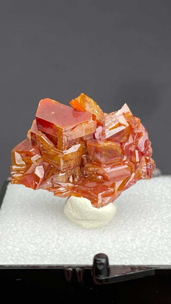 Stacked orange-red vanadinite plates from Morocco, in a display box, detail of the matrix contact