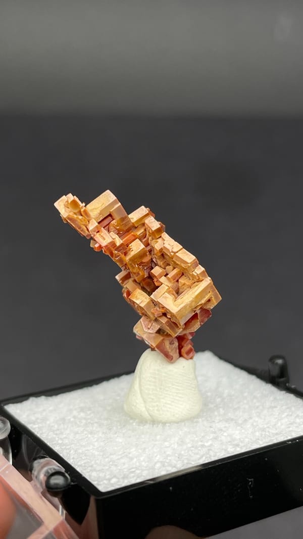 Stacked peach-red vanadinite crystal column from Morocco, in a display box, top view