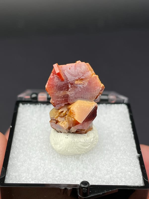 Stacked red-orange and amber vanadinite crystals from Morocco, in a box