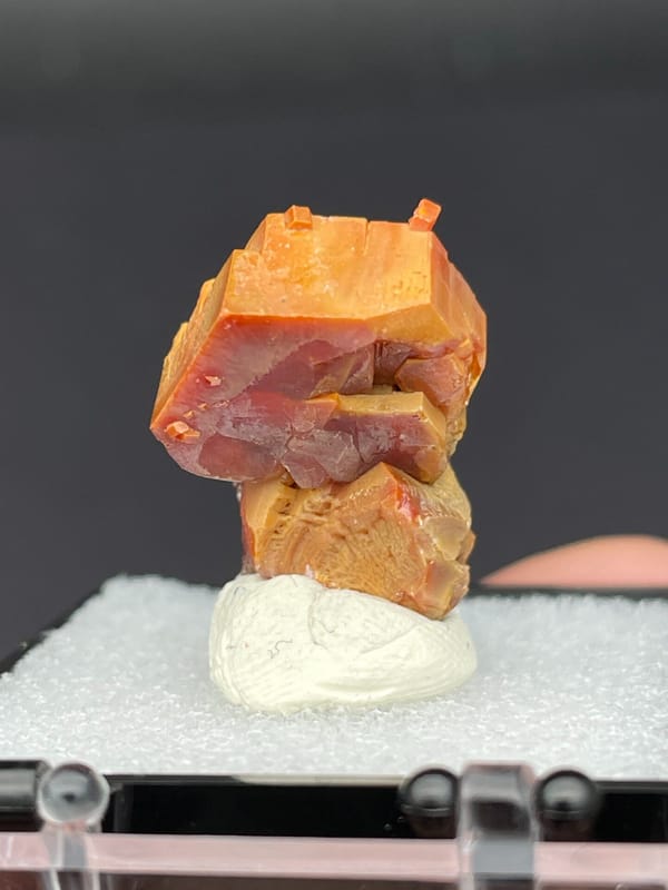 Stacked red-orange and amber vanadinite crystals from Morocco, in a box, close-up of the crystal faces