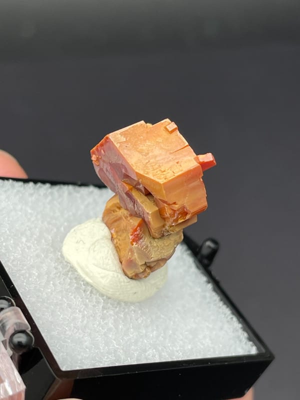 Stacked red-orange and amber vanadinite crystals from Morocco, in a box, top view