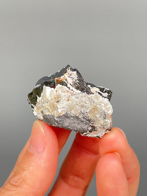 Black cassiterite crystal with silvery mica from Xuebaoding, Sichuan, China, detail of the matrix contact