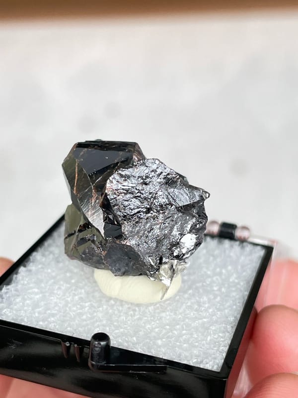 Black cassiterite crystal group from Xuebaoding, Sichuan, China, in a box, close-up of the crystal faces