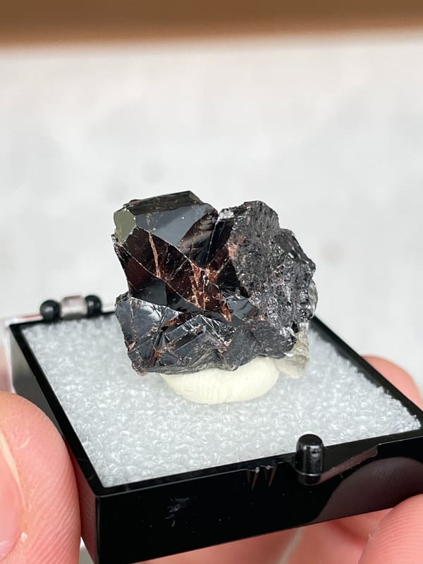 Black cassiterite crystal group from Xuebaoding, Sichuan, China, in a box, detail of the matrix contact