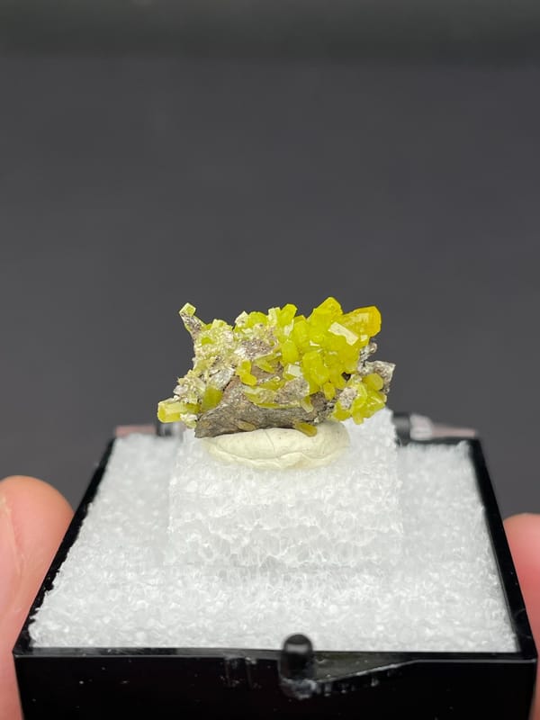 Yellow-green pyromorphite crust on grey matrix from Guangdong, China, in a box, second angle