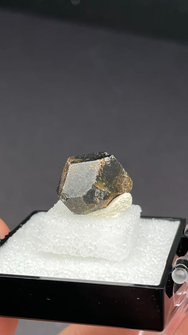 Brown dodecahedral andradite garnet crystal from Handan, Hebei, China, in a box, close-up of the crystal faces