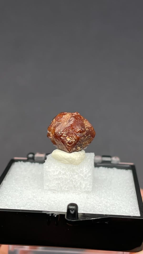 Small reddish-brown dodecahedral andradite garnet from Handan, Hebei, China, detail of the matrix contact