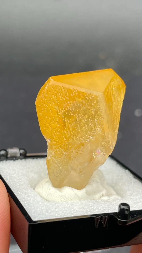 Amber-coloured baryte crystal from Jinkouhe, Sichuan, China, in a display box, detail of the matrix contact