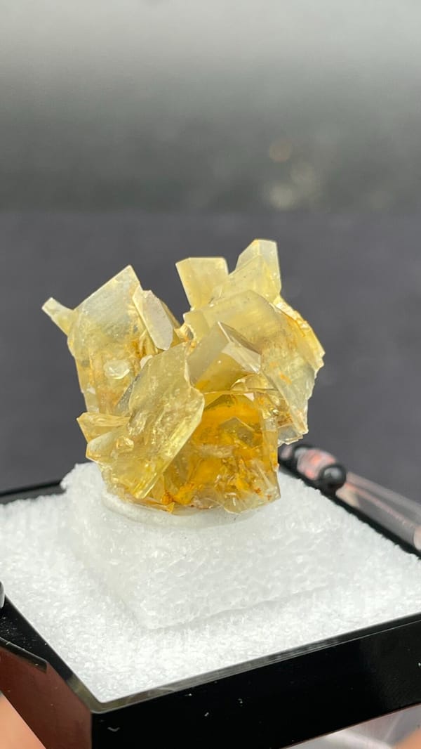 Golden-yellow baryte crystal cluster from Yunnan, China, in a display box, close-up of the crystal faces