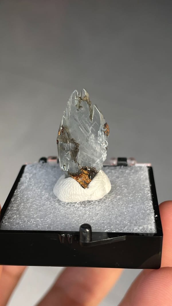 Pale blue transparent baryte crest on orange matrix from Morocco, in a box, close-up of the crystal faces