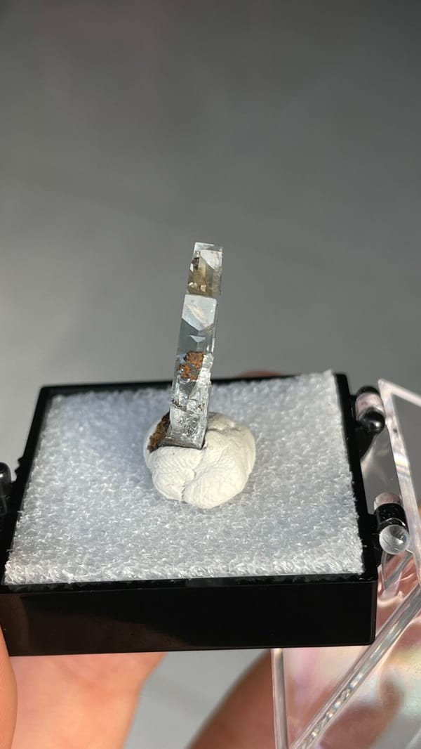 Pale blue transparent baryte crest on orange matrix from Morocco, in a box, top view