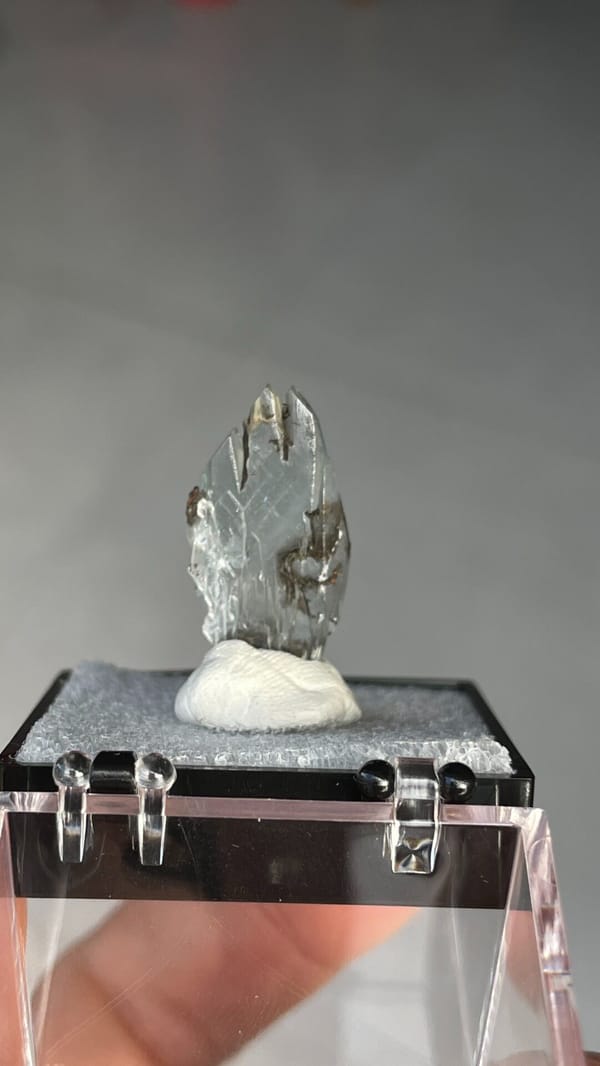 Pale blue transparent baryte crest on orange matrix from Morocco, in a box, detail of the matrix contact