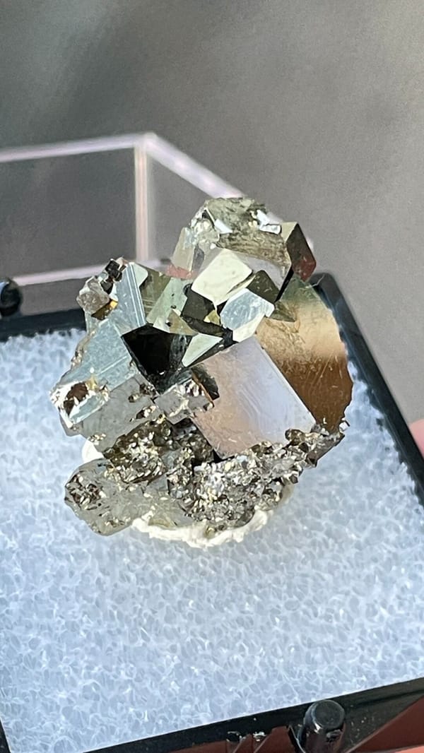 Bright brassy pyrite crystal cluster from Hubei, China, in a display box, close-up of the crystal faces