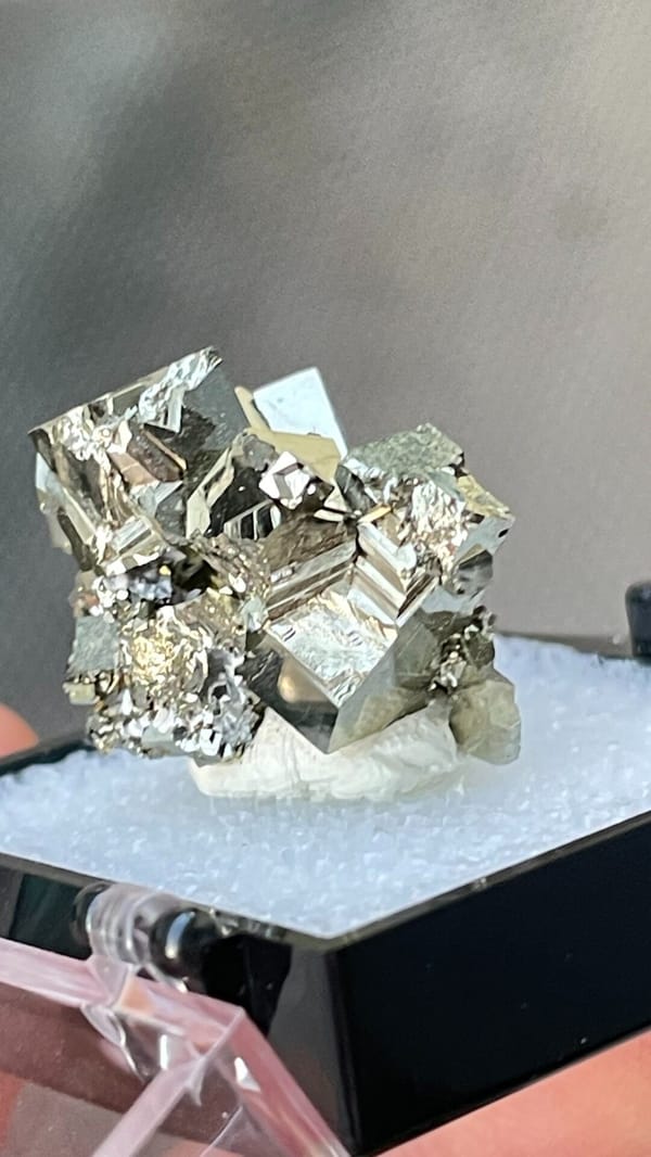 Bright brassy pyrite crystal cluster from Hubei, China, in a display box, detail of the matrix contact