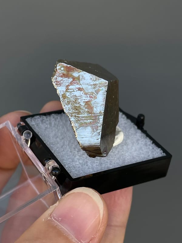 Brassy striated pyrite crystal from Yunnan, China, in a display box, close-up of the crystal faces
