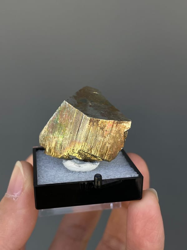 Brassy striated pyrite crystal from Yunnan, China, in a display box, detail of the matrix contact