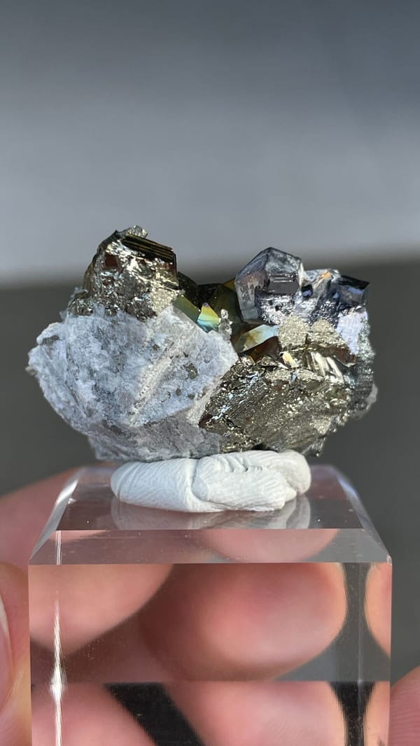 Iridescent pyrite crystals with grey galena from Peru, on an acrylic stand, detail of the matrix contact