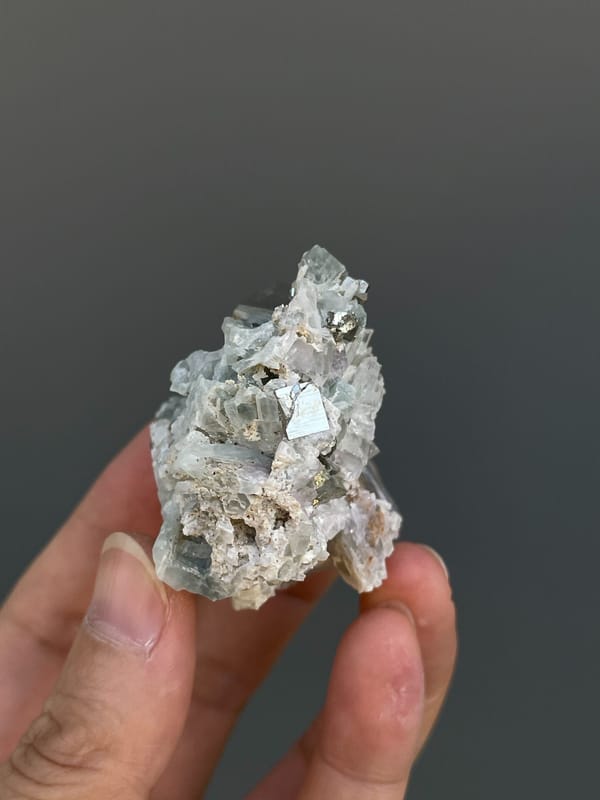 Pale metallic pyrite crystal on grey matrix from Shangbao, Hunan, China, close-up of the crystal faces
