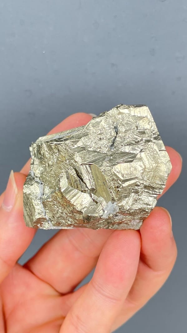 Large brassy striated pyrite single crystal from Yunnan, China, detail of the matrix contact