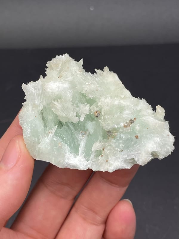 Pale blue-green bladed aragonite crust from Yunnan, China, held in hand